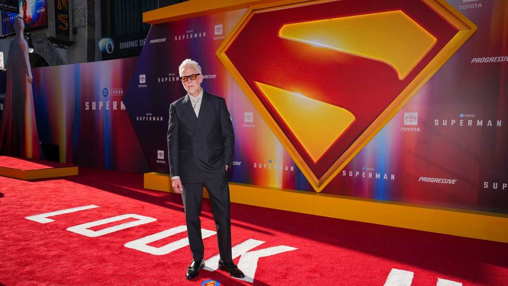 James Gunn stands on a red carpet in front of a Superman logo