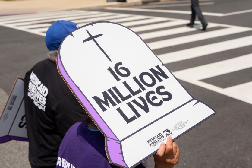 Someone holding up a sign outside that shaped like a grave that says "16 million lives" on it.