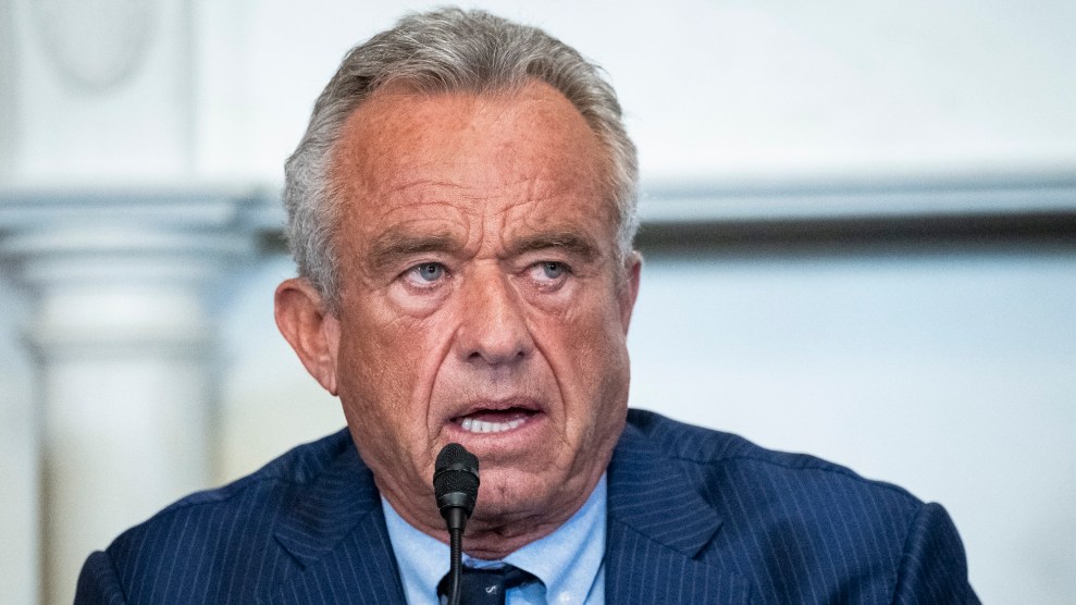 Close up image of Robert F. Kennedy Jr. speaking into a small microphone. He is wearing a suit and looking towards the side of the frame.