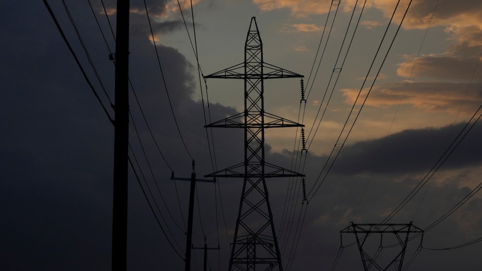 Power lines strung across tall metal structures set against a darkening sky, with a bit of blue and clouds at the center.