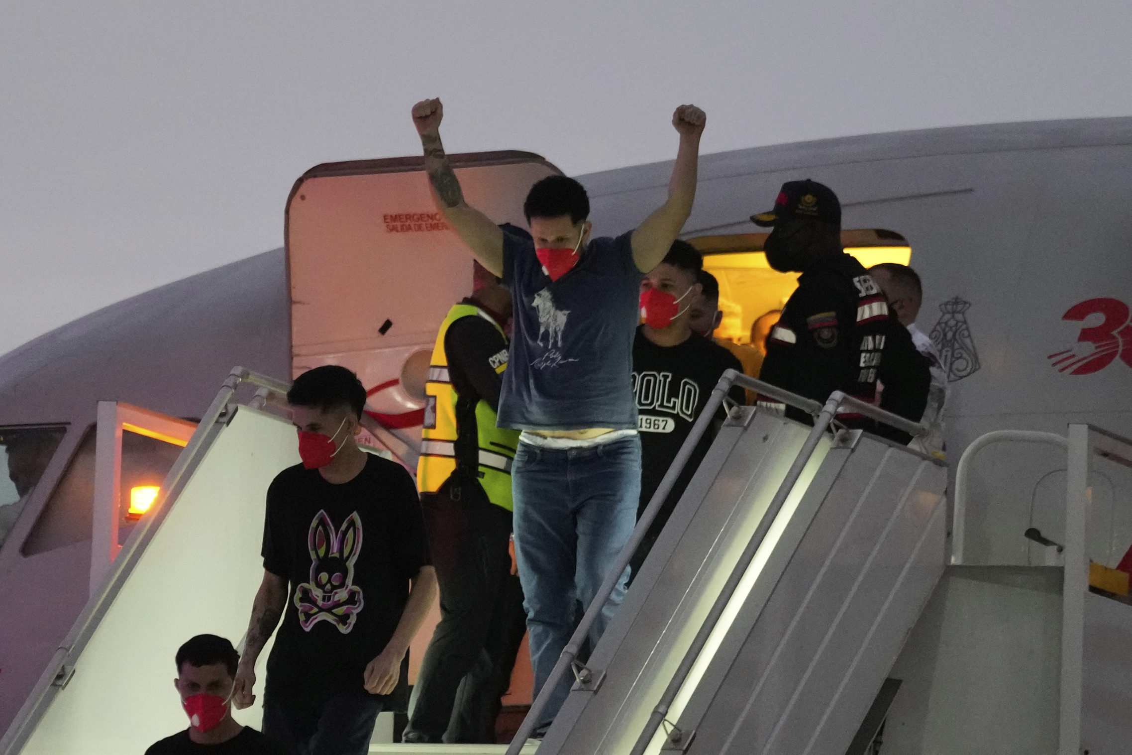 a man raising his arms in front of an airplane as her deboards
