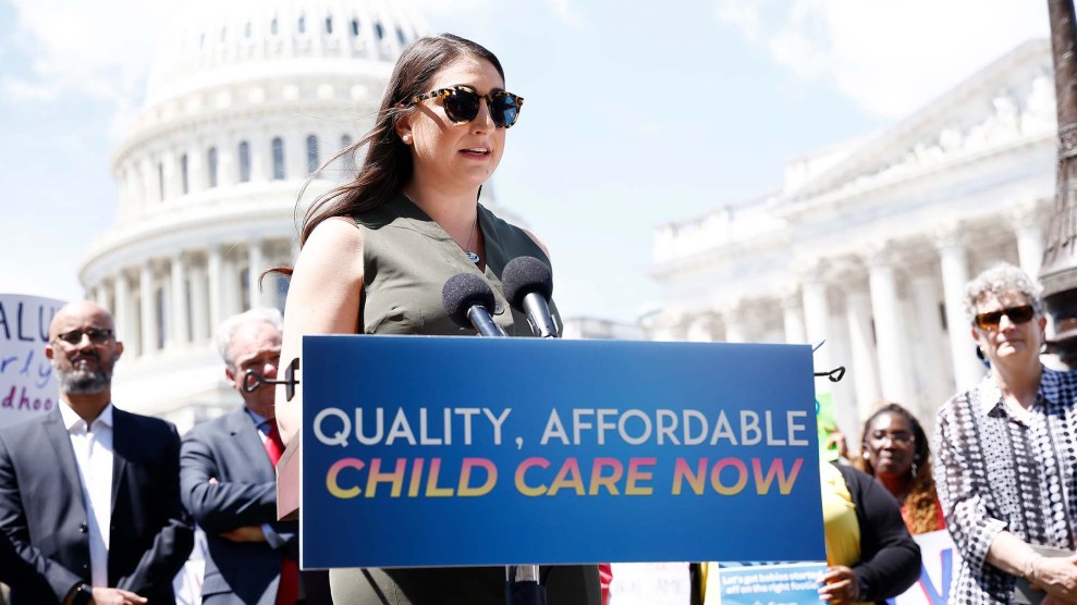Portrait of Rep. Sarah Jacobs behind a sign that says "quality, affordable childcare now."
