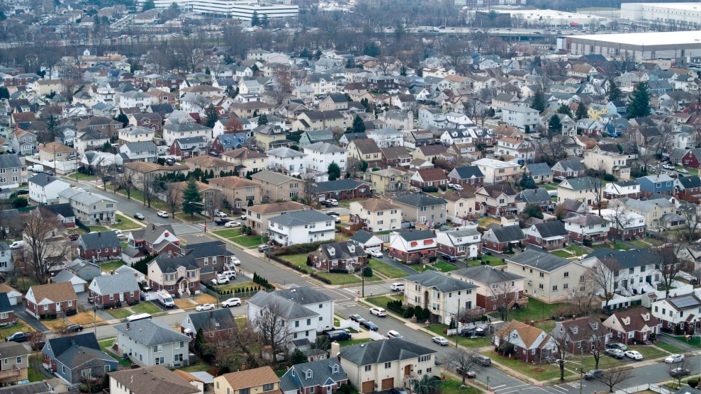 Aerial shot of a neighborhood of homes, trees with no leaves, and streets with parked cars.