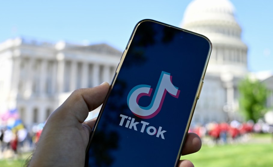 In this photo illustration, a phone displaying the TikTok logo is held up in front of the U.S. Capitol Building.