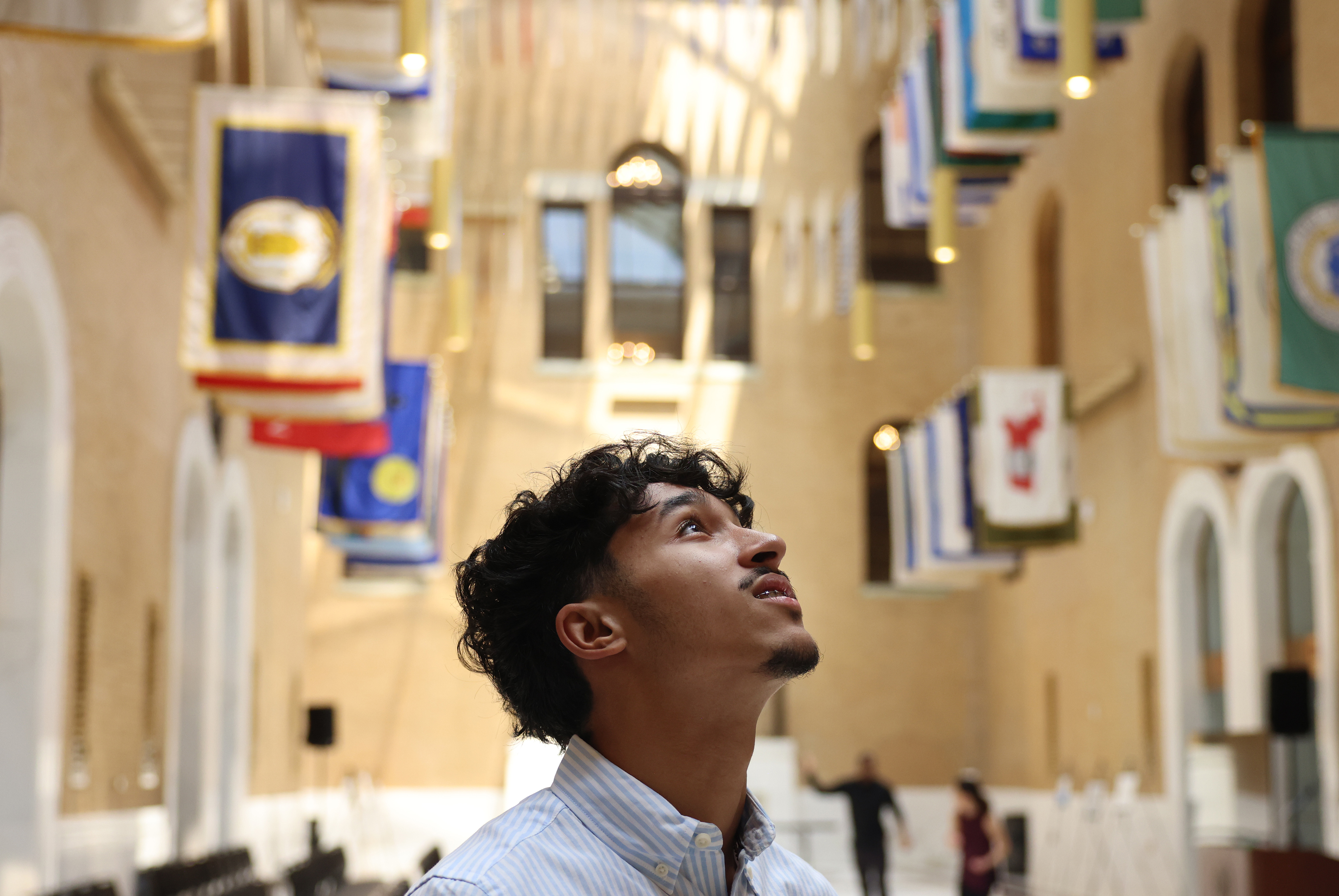 A boy looking up at flags that hang above him. 