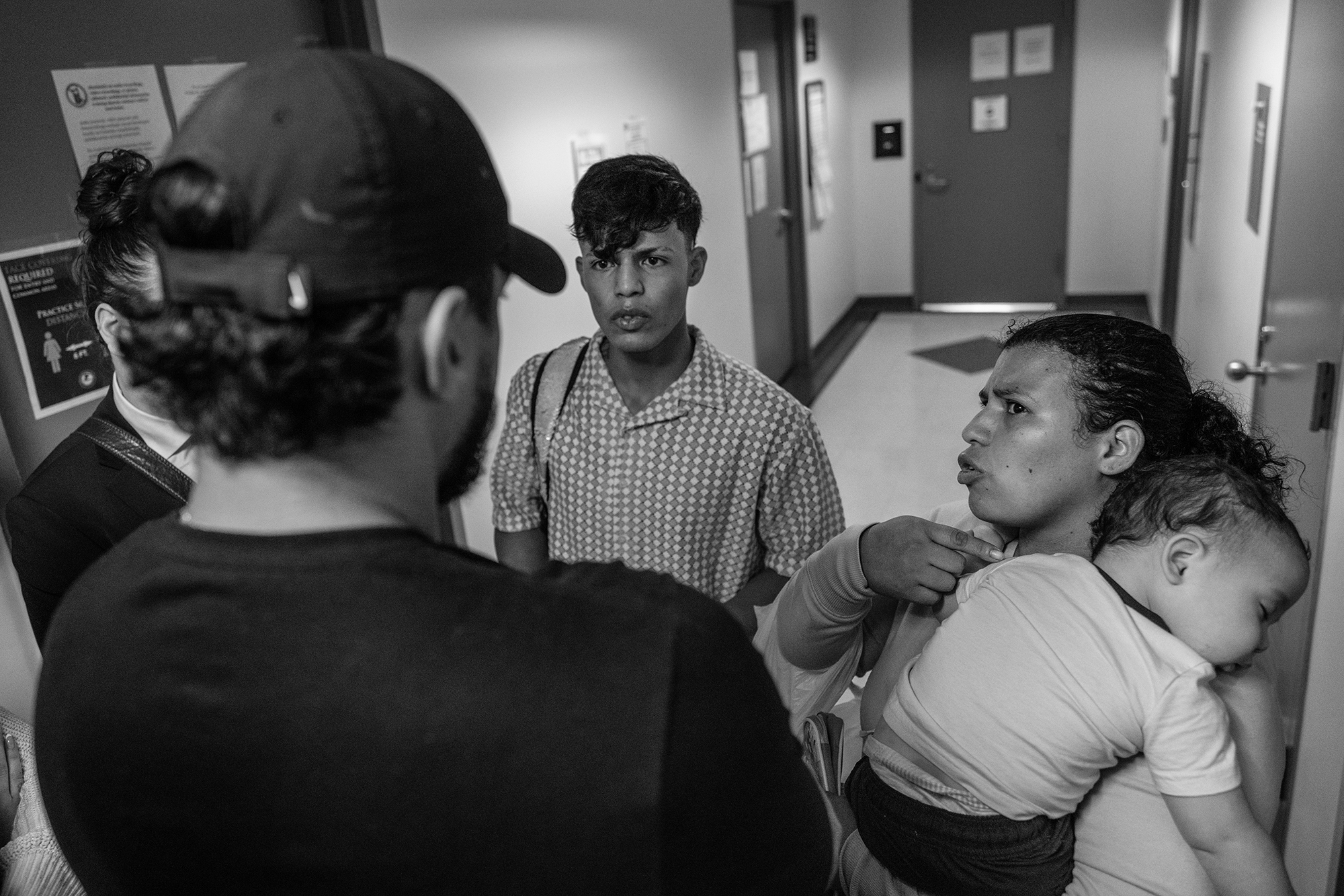 A woman points at a small baby she's holding as Federal agents stand, facing her.