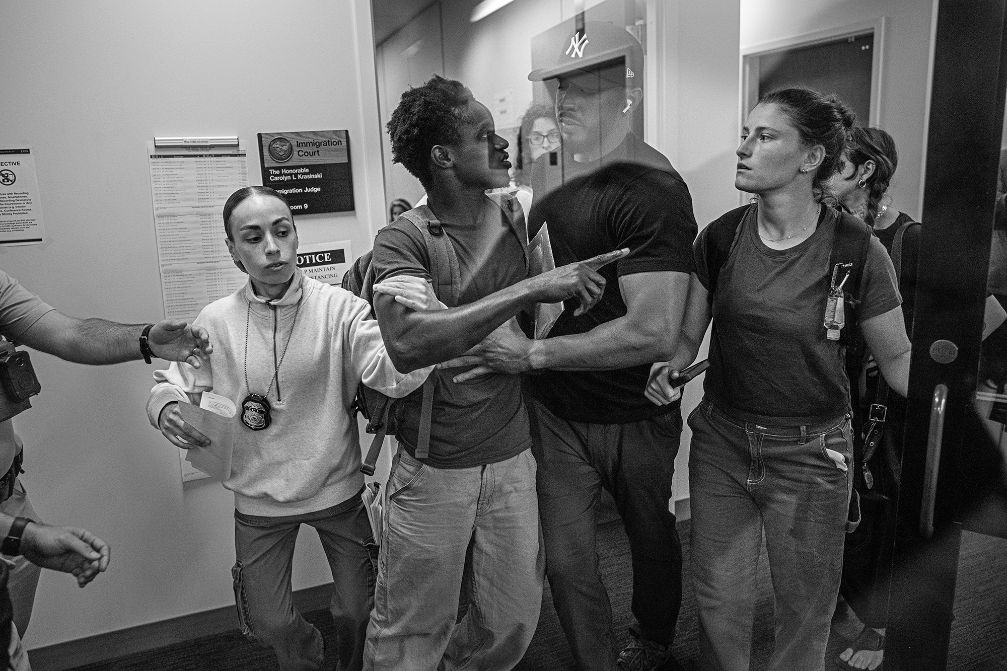Man being detained by a federal agent is flanked by two female agents.