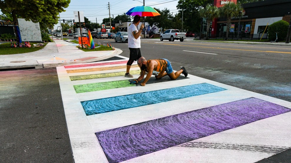 Orlando activists use chalk to color in a crosswalk near the Pulse nightclub after the DeSantis administration removed a rainbow memorial.