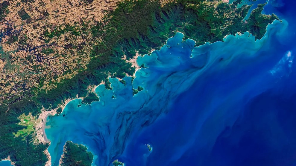 An aerial image of a green coastline next to blue water.