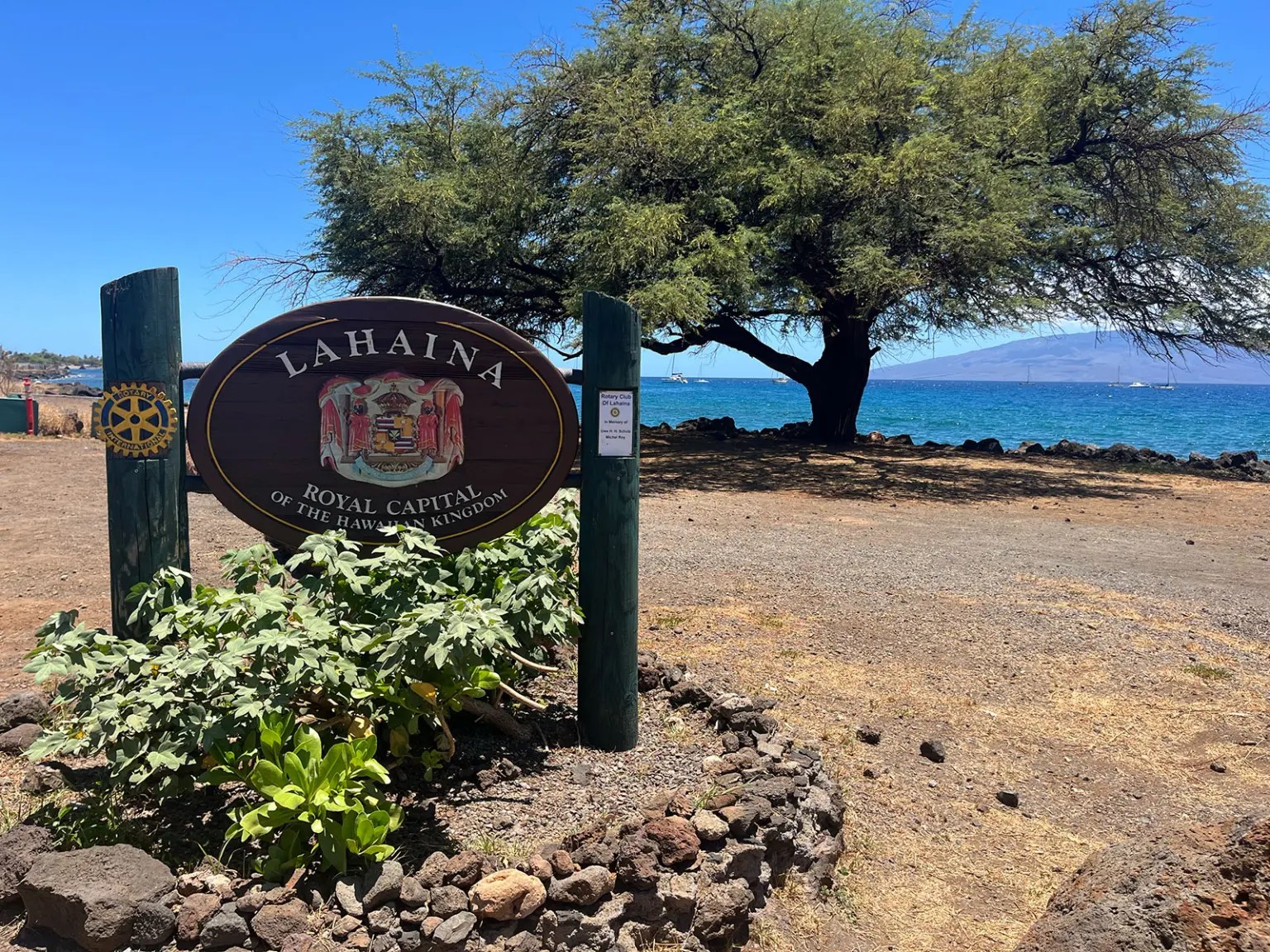 A brown and green sign surrounded by flowers says "Lahaina Royal Capital of the Hawaiian Kingdom"