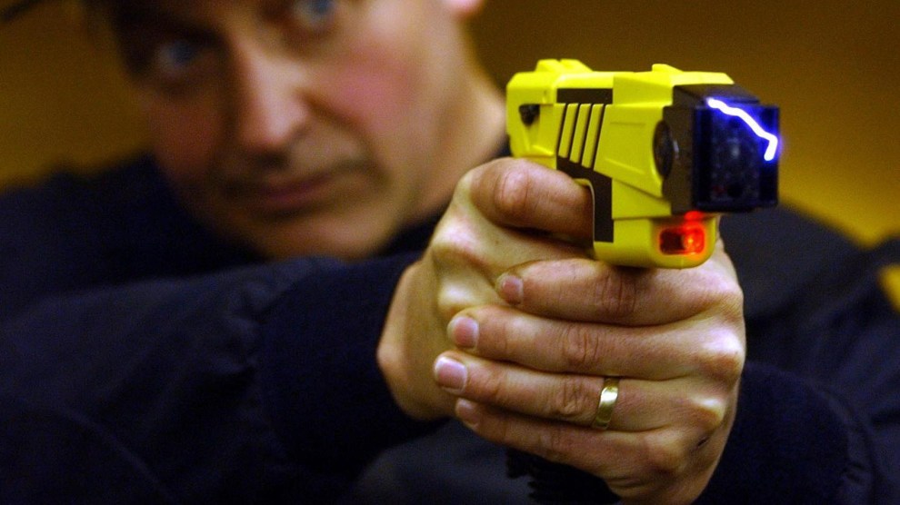A man holds a yellow taser pointing toward the camera.