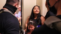 A woman and a girl with frightened expressions face masked agents.