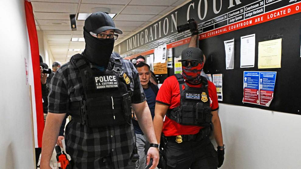Masked federal agents stand in front of people in a hallway outside immigration court