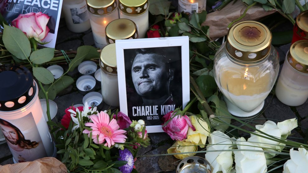 Flowers and candles surround a black and white photo of Charlie Kirk