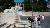 People splash water on their face from a foundain.