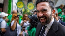 Zohran Mamdani smiles wearing a suit at a Labor Day parade.