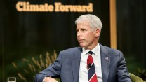 Chris Wright sits in front of a sign that says "Climate Forward."