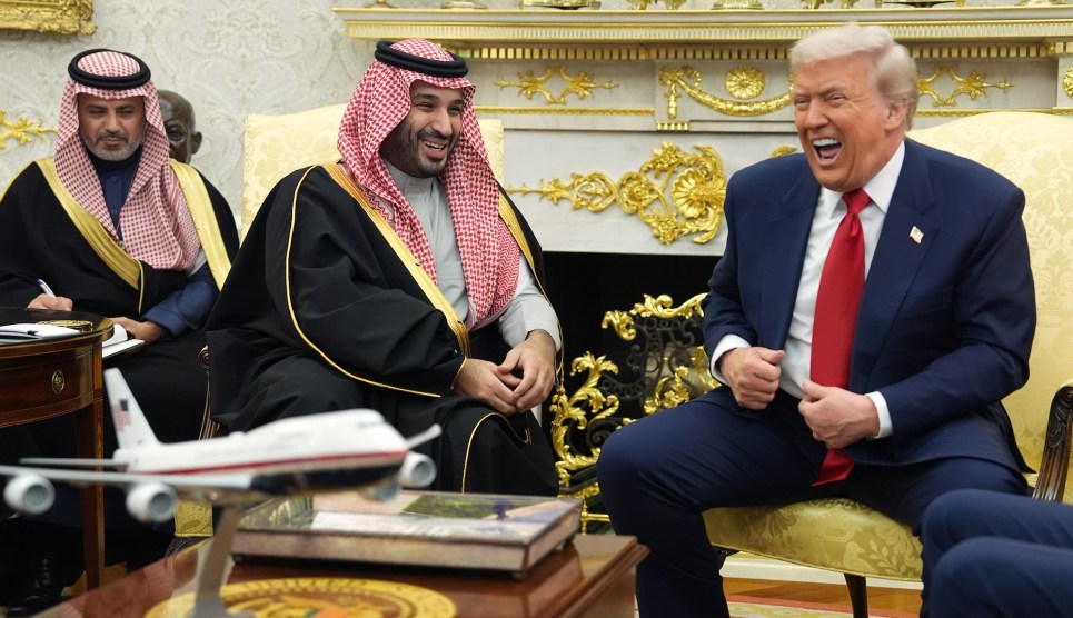 Crown Prince Mohammed bin Salman and Donald Trump laugh while seated in upholstered chairs in the Oval Office.