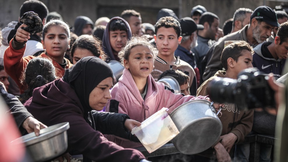 A group of women and children with bowls and other supplies huddled together