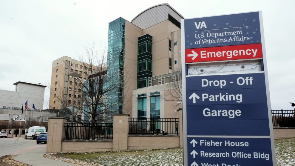 A medical center building is in the background with a US Department of Veterans Affairs sign labeling directions for parking and drop-off in the foreground.