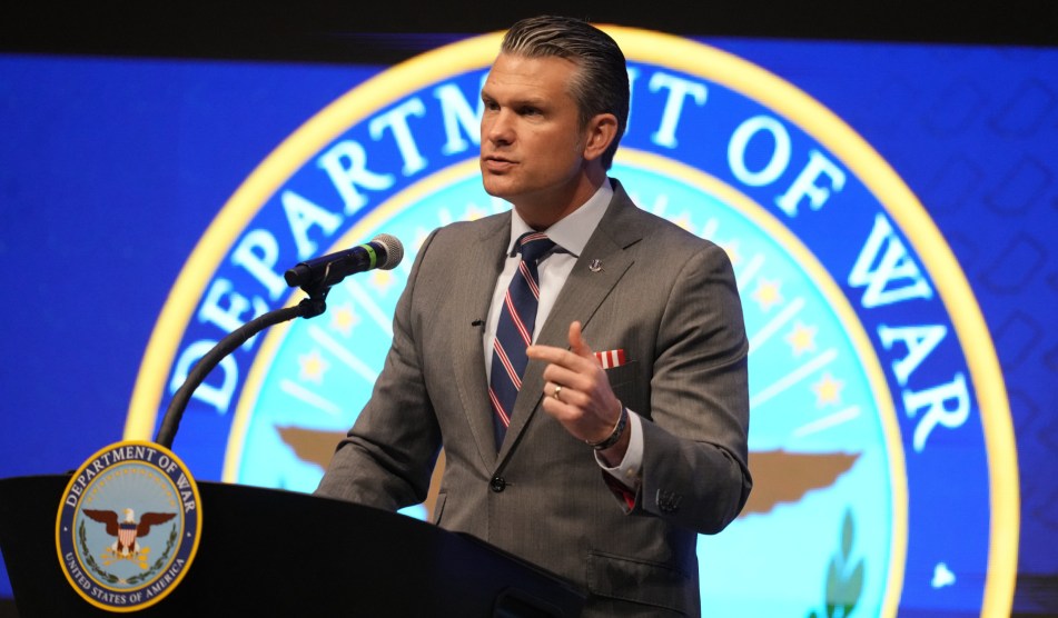 Defense Secretary Pete Hegseth giving a speech on a podium in front of a large Department of War sign.