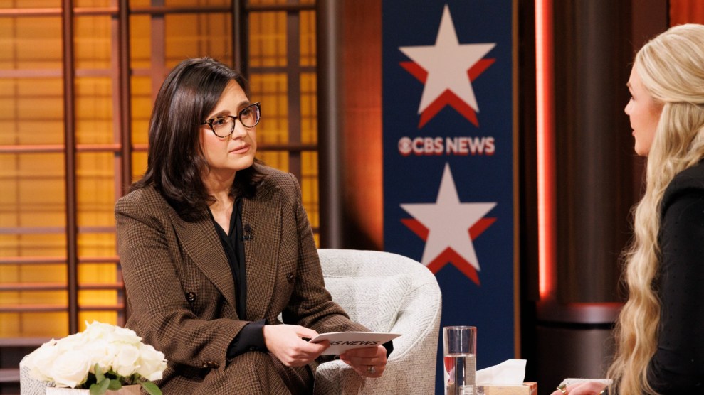 Bari Weiss is sitting down in a chair on the left, dressed in a brown suit. She is holding cue cards as she interviews Erika Kirk, positioned on the right.