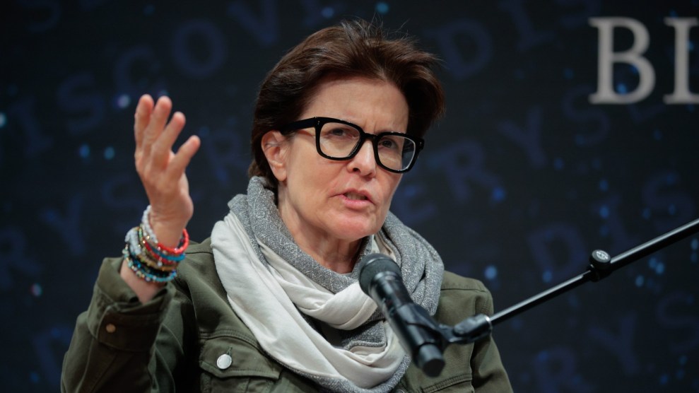 Kara Swisher speaking into a microphone. She is wearing a gray jacket and scarf.