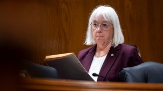 Sen. Patty Murray, a white woman with white hair, in a wood-paneled hearing room holding a folder.