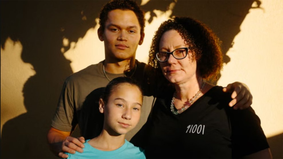 A family of three pose for a portrait outdoors in soft light, mother with a boy and a girl.