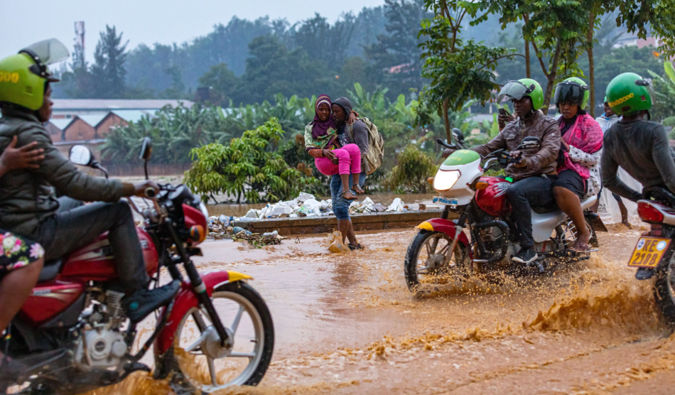 Folks on motorized bikes drive through a flooded street