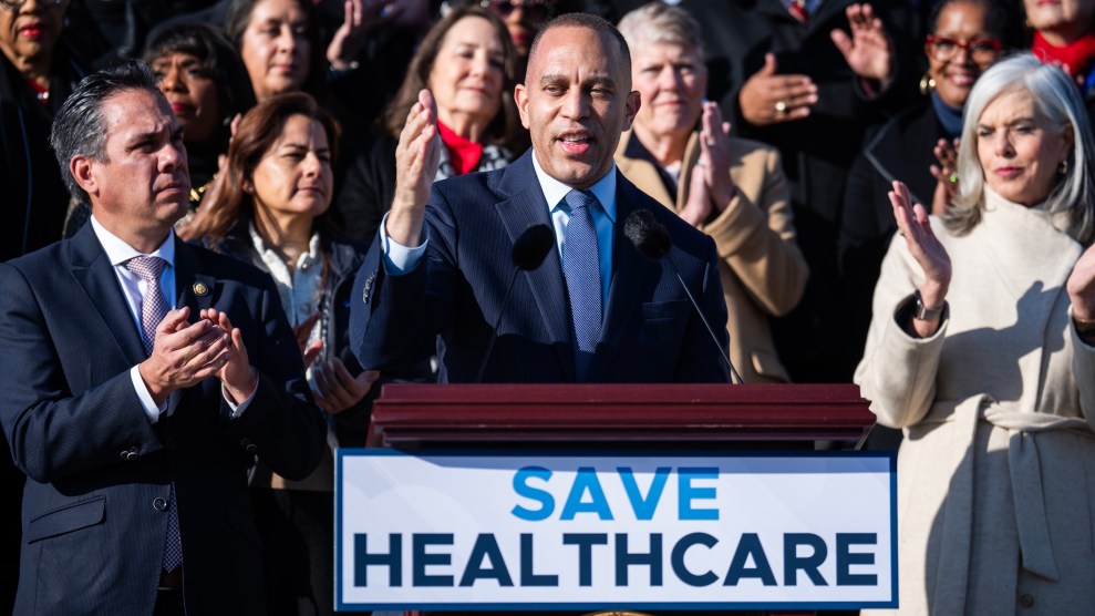 Hakeem Jeffries, a black man, surrounded by colleagues, at a podium that says "save healthcare"